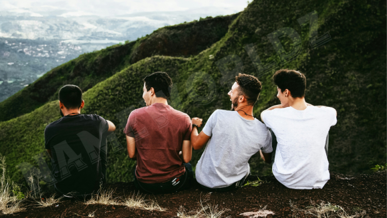 row of four men sitting on mountain trail